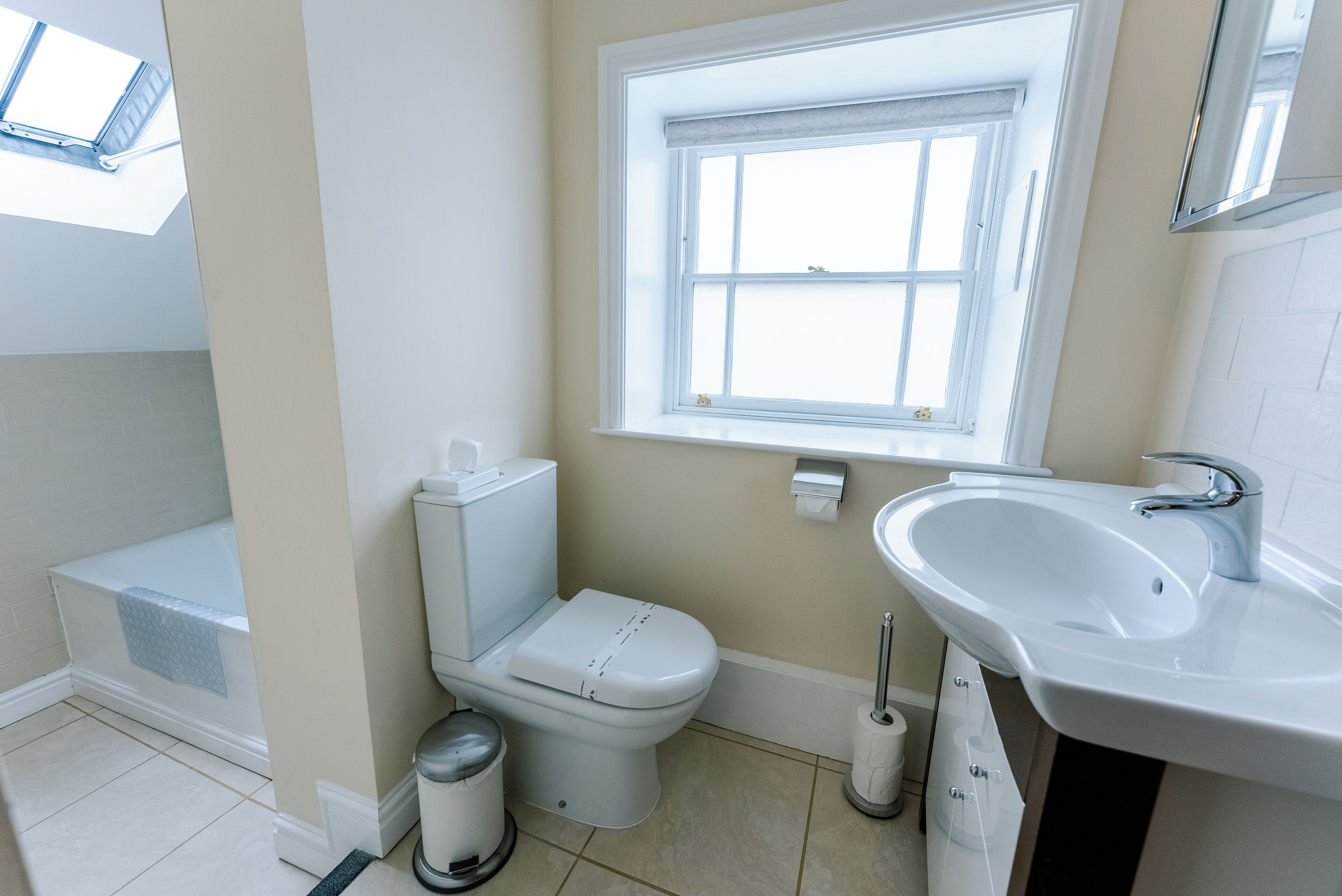 A bathroom with a toilet, sink, and window.