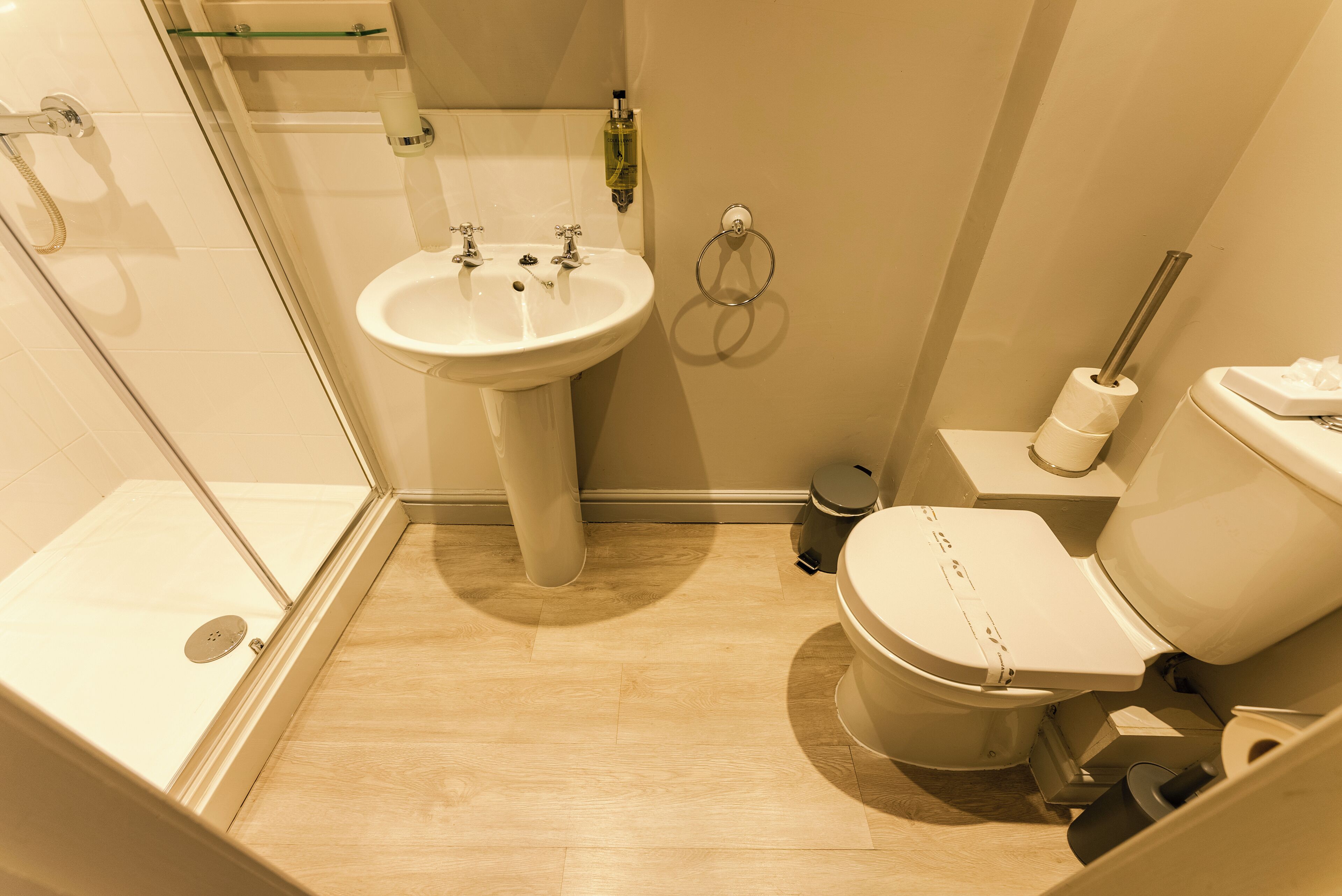 A bathroom with a shower, sink, toilet, and a glass door shower enclosure.