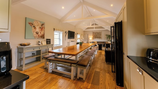 Una cocina amplia con una isla de madera, asientos integrados y un cuadro grande.