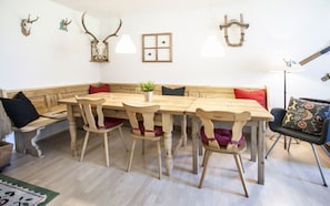 Une table à manger en bois, accompagnée de bancs, un pot de fleurs et des éléments décoratifs en forme de bois de cerf accrochés au mur.