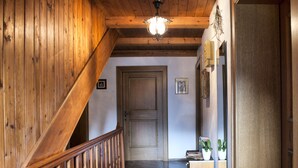 Un escalier en bois menant à une porte, une petite table avec des plantes et un miroir fixé au mur.