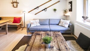 Un salon chaleureux avec une table basse en bois, un canapé bleu agrémenté de coussins à motifs, un banc en bois et un tapis rustique.