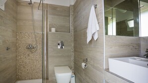 Un bagno moderno con doccia vetro, water e un ampio lavandino.
