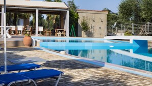 Una piscina con lettini da relax e una zona salotto coperta.
