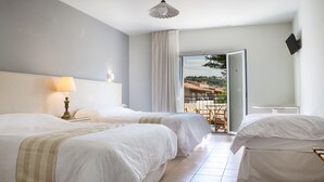 Camera d'albergo con due letti, una lampada, un tavolo e vista all'esterno.