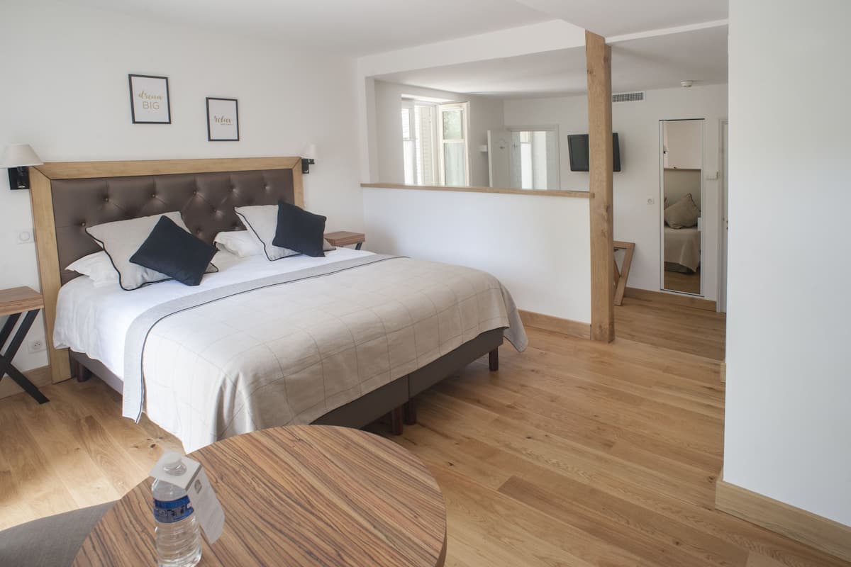 Een slaapkamer met een bed, nachtkastjes, een houten vloer en een spiegel.