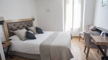 A neatly arranged bedroom with a bed, bedside table, lamp, and a desk with a chair.