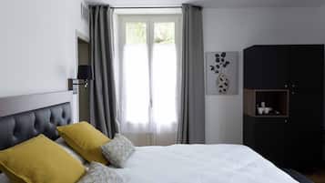 Un dormitorio con una cama, dos almohadas, una mesita de noche, una lámpara, un armario y una ventana con cortinas.
