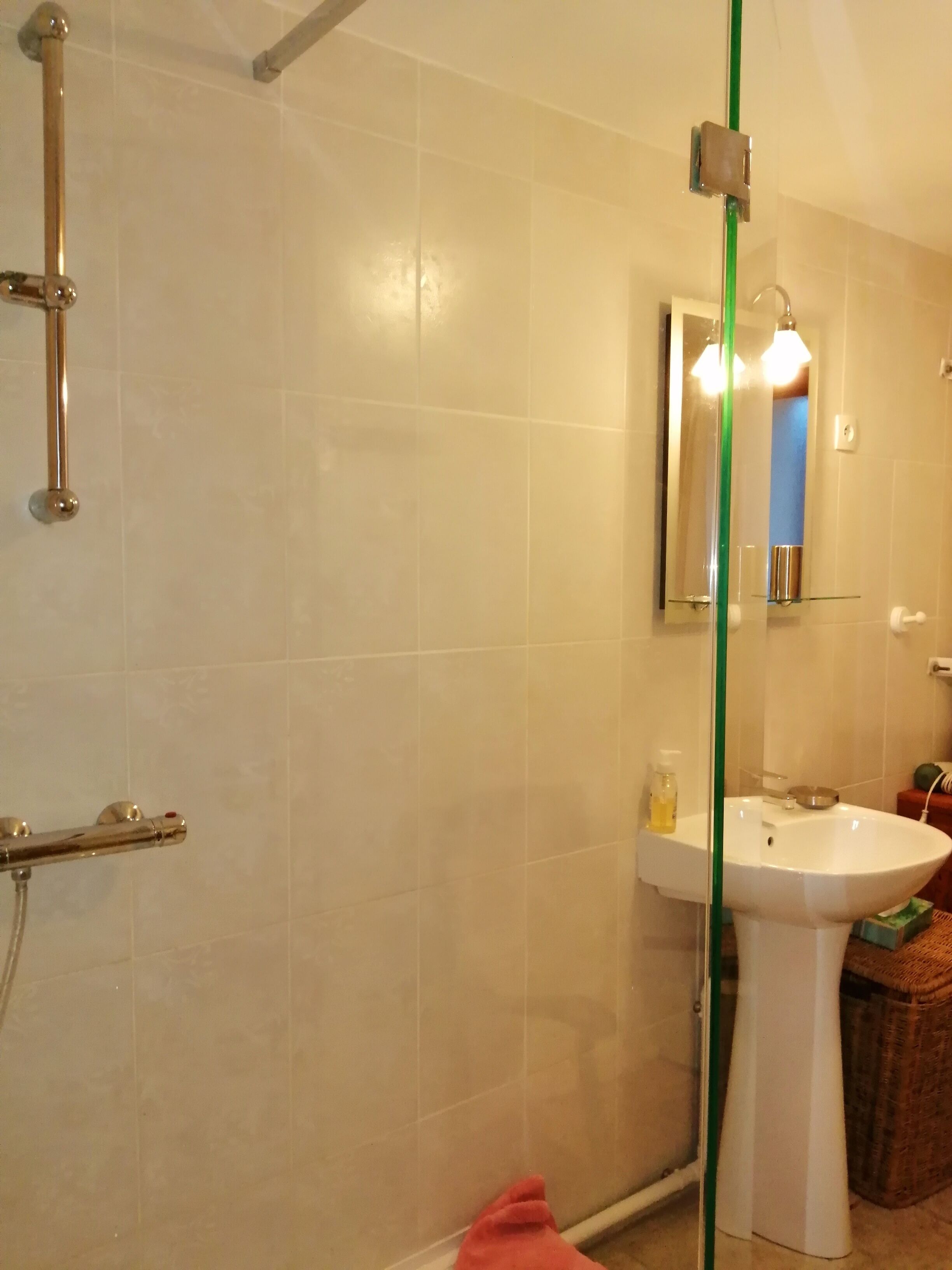 A bathroom with a shower, a sink, and a mirror.