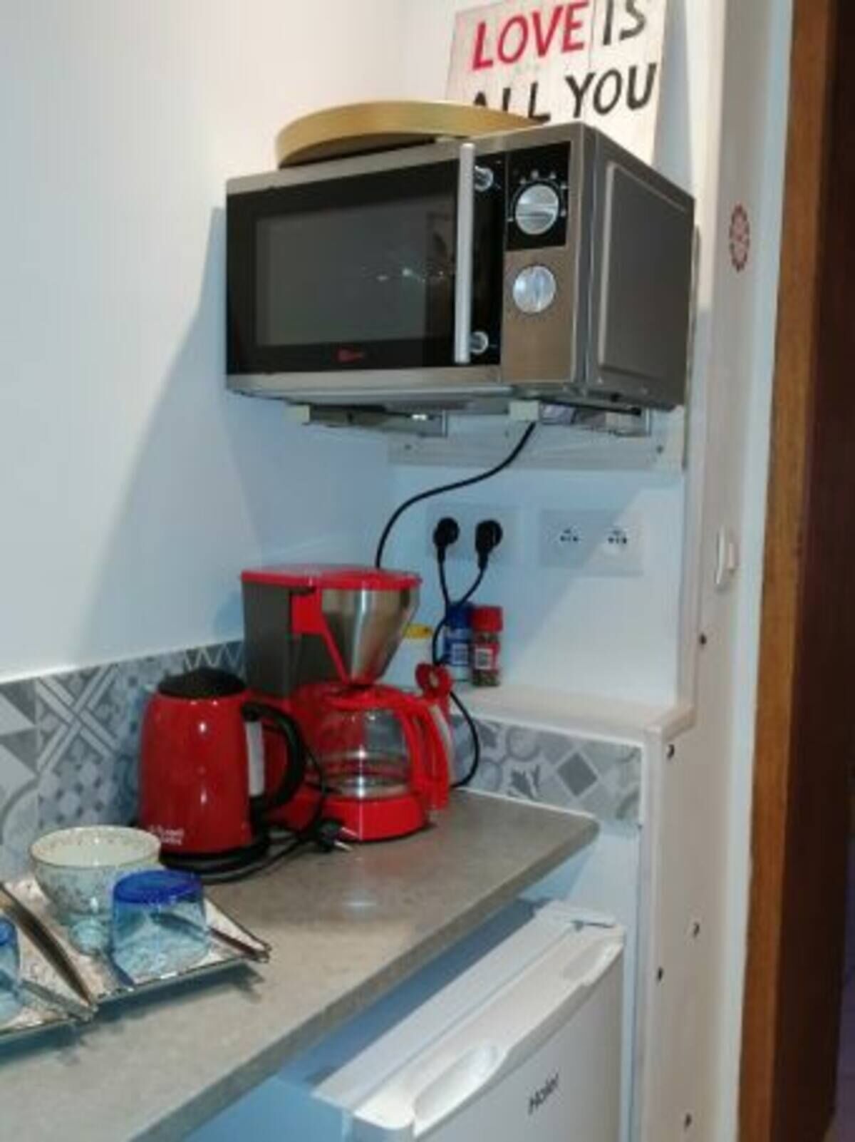 Une cuisine équipée d’un four à micro-ondes, d’une machine à café et d’une cafetière posée sur le plan de travail.