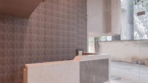 A modern bathroom with a geometric patterned wall, a marble vanity, and a large window allowing natural light. - Hotel West Blue (Mumbai)