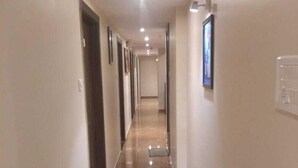A long, narrow hallway with a shiny, reflective floor and light-colored walls. - Hotel West Blue (Mumbai)