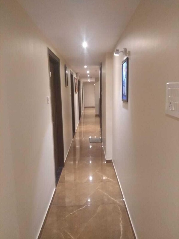 A long, narrow hallway with a shiny, reflective floor and light-colored walls.