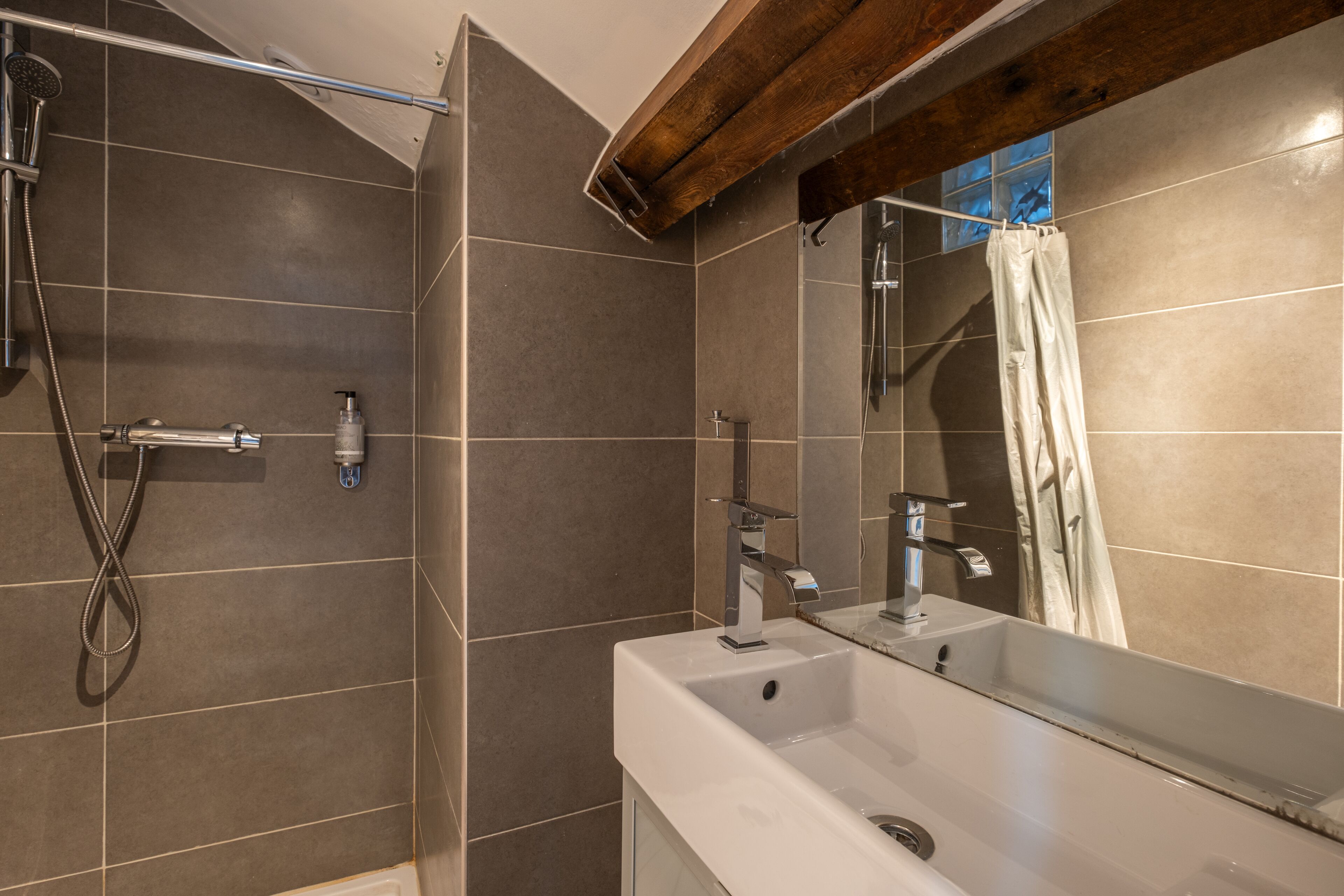 A modern bathroom with a shower, a sink, and a mirror.