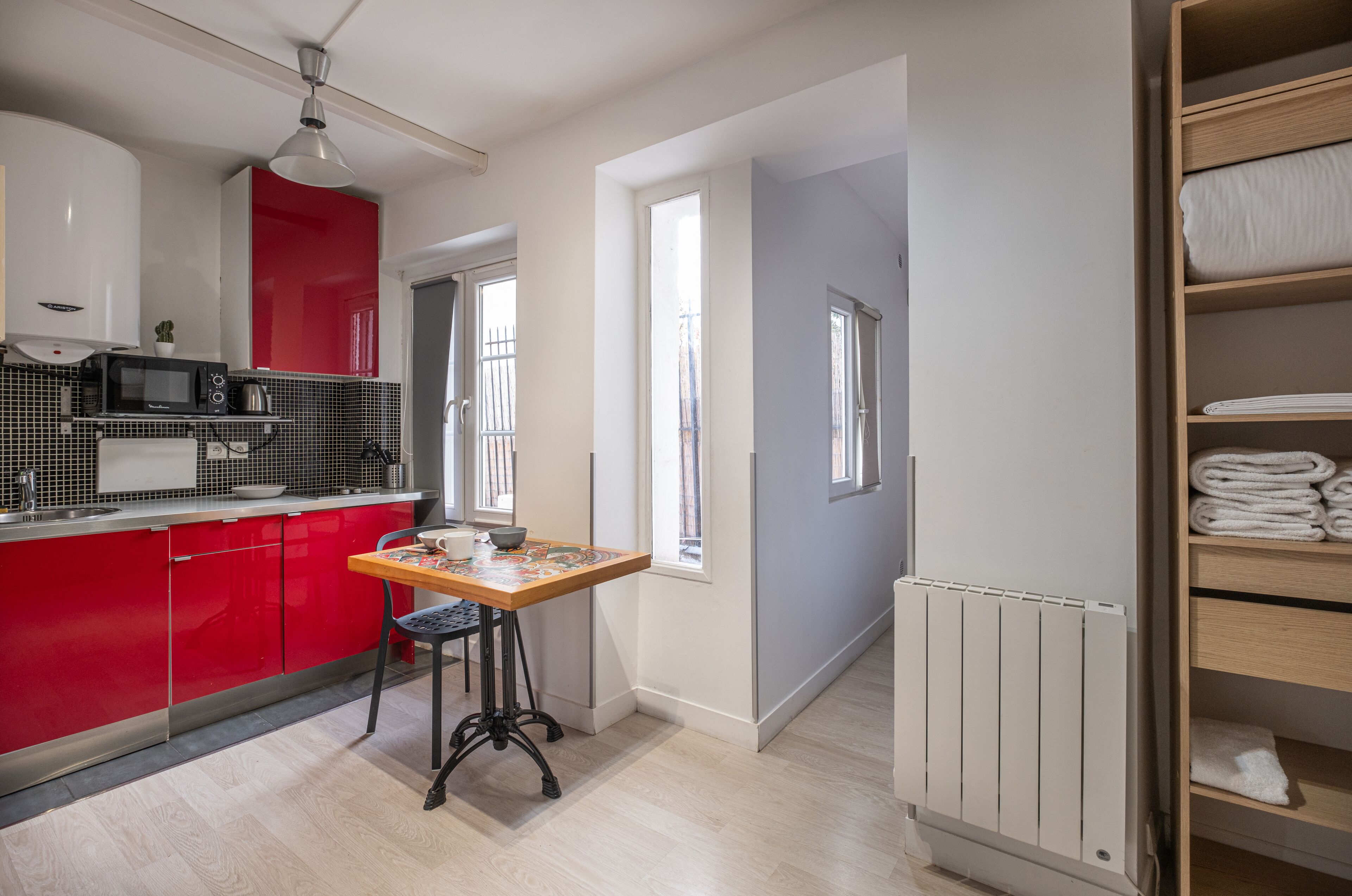 Een moderne keuken met rode kastjes, een houten tafel en een zwarte stoel.