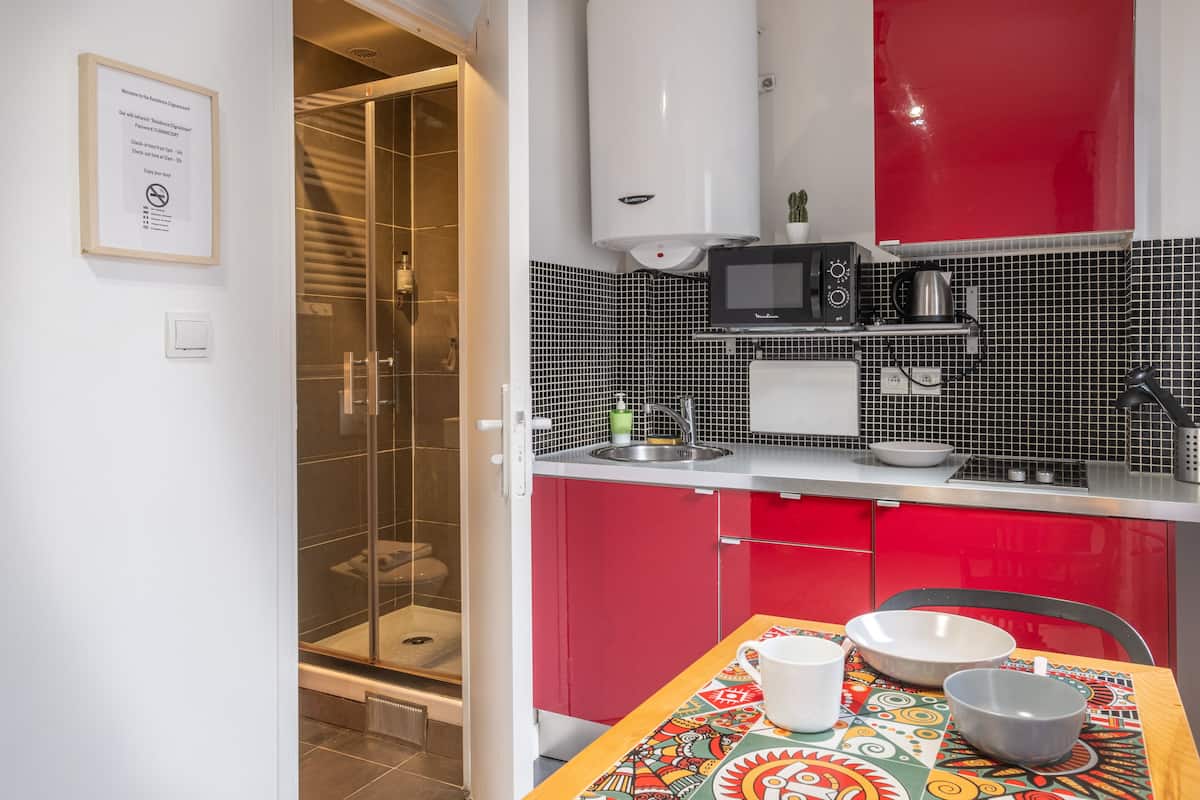 A compact kitchen with red cabinets, a microwave, and a sink.