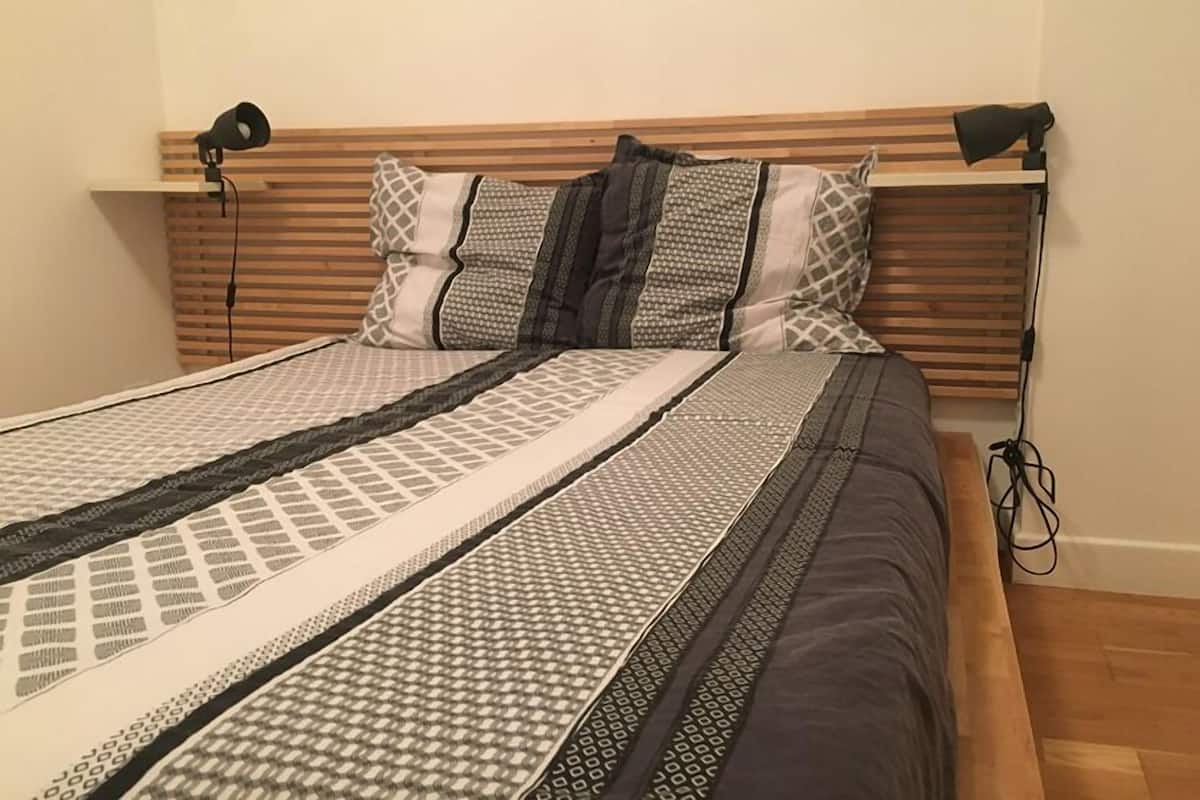 A bed with a wooden headboard, multiple pillows, and a patterned bedspread.