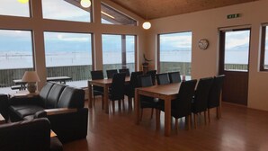 A spacious room with large windows, a wooden ceiling, and a dining area with tables and chairs. - Guesthouse Uggi (Rangárþing ytra)