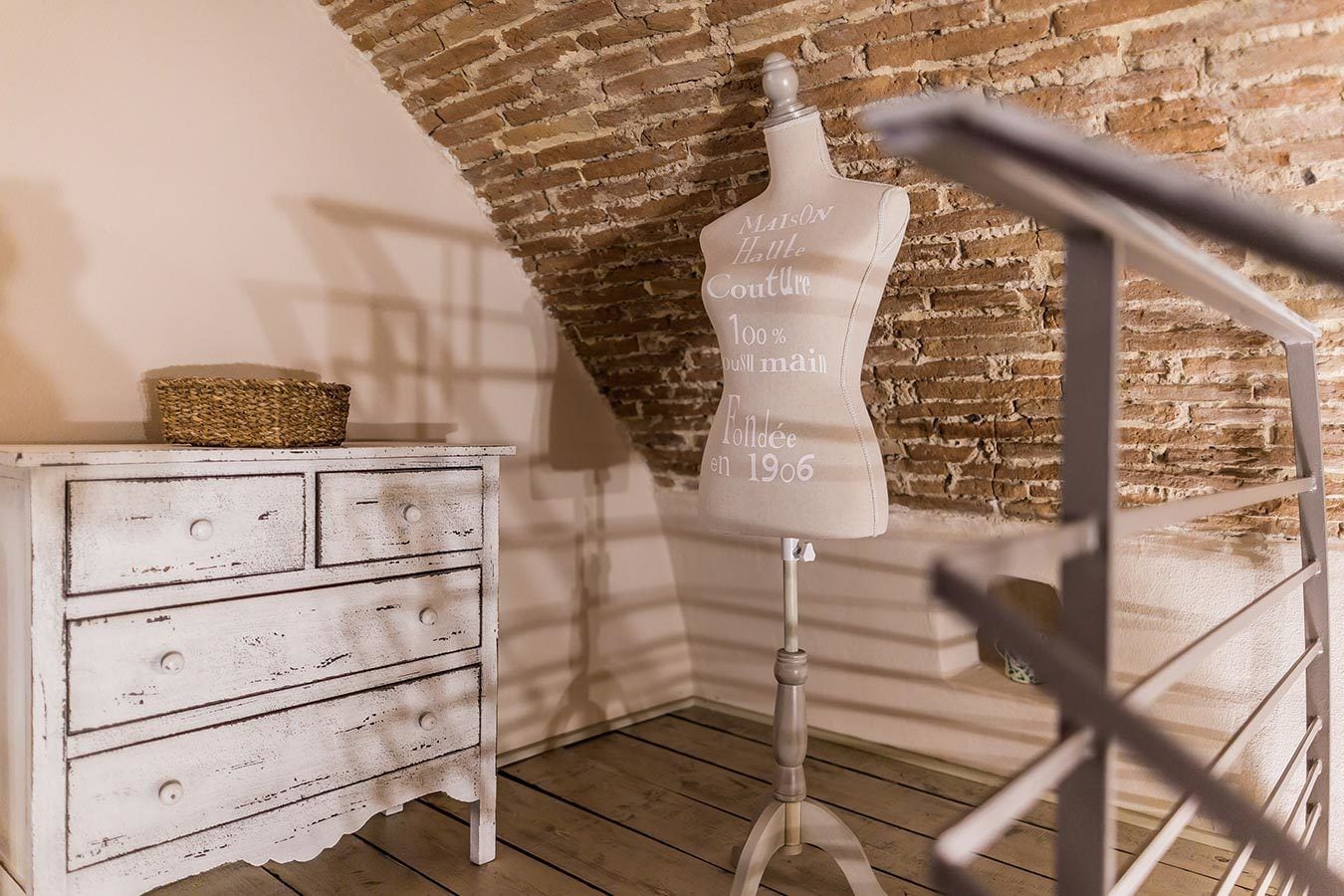 Una habitación rústica con un aparador blanco, un maniquí con texto y una pared de ladrillo.