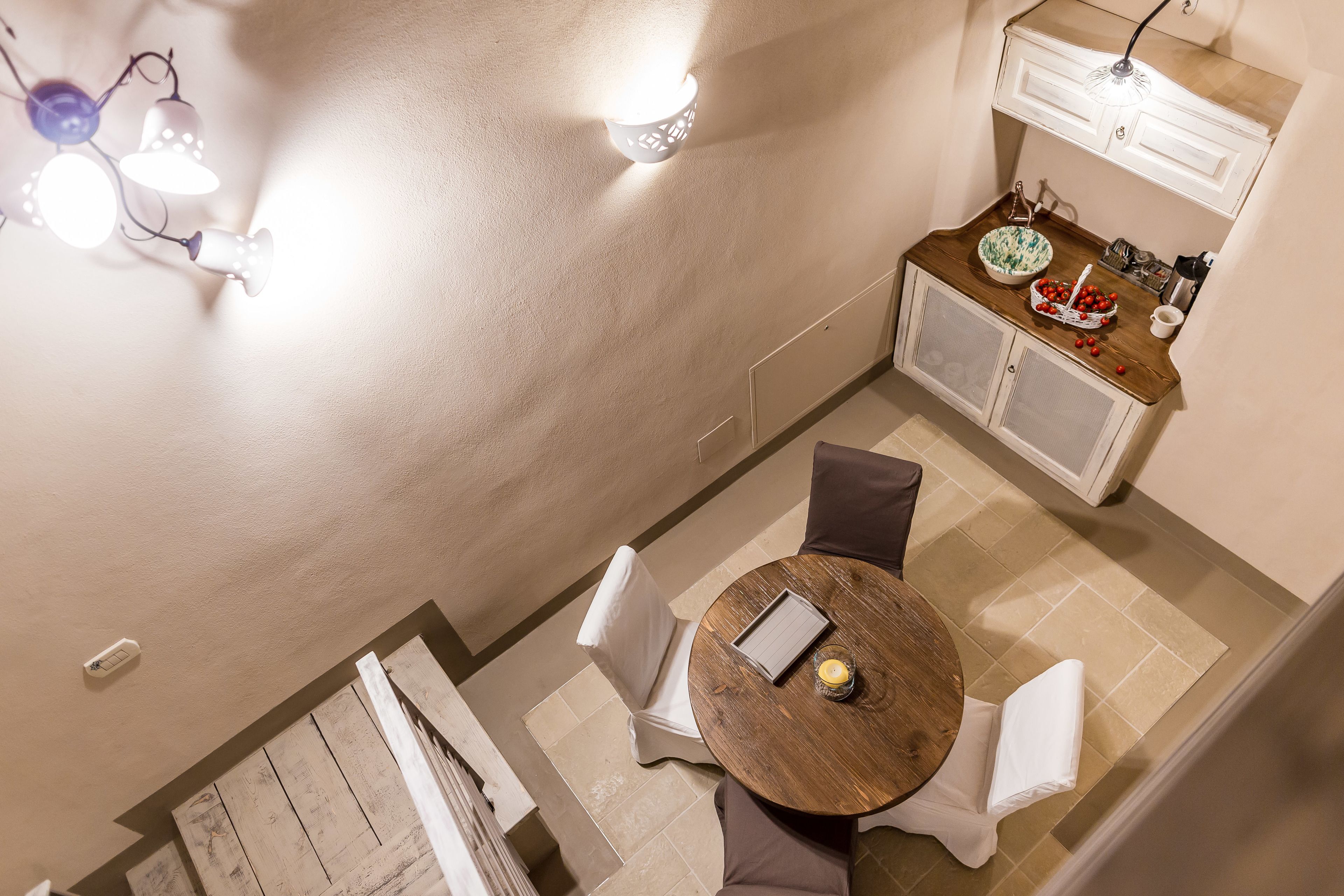 A dining area with a round table, chairs, and a small kitchen area with a sink and cabinets.