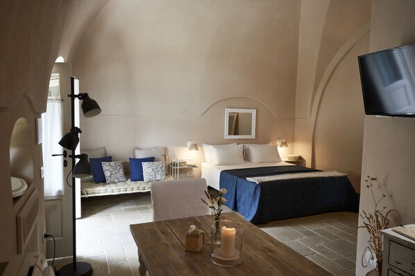 A cozy bedroom with a bed, bedside table, lamp, and a TV mounted on the wall. - Borgo San Gaetano (Bernalda)