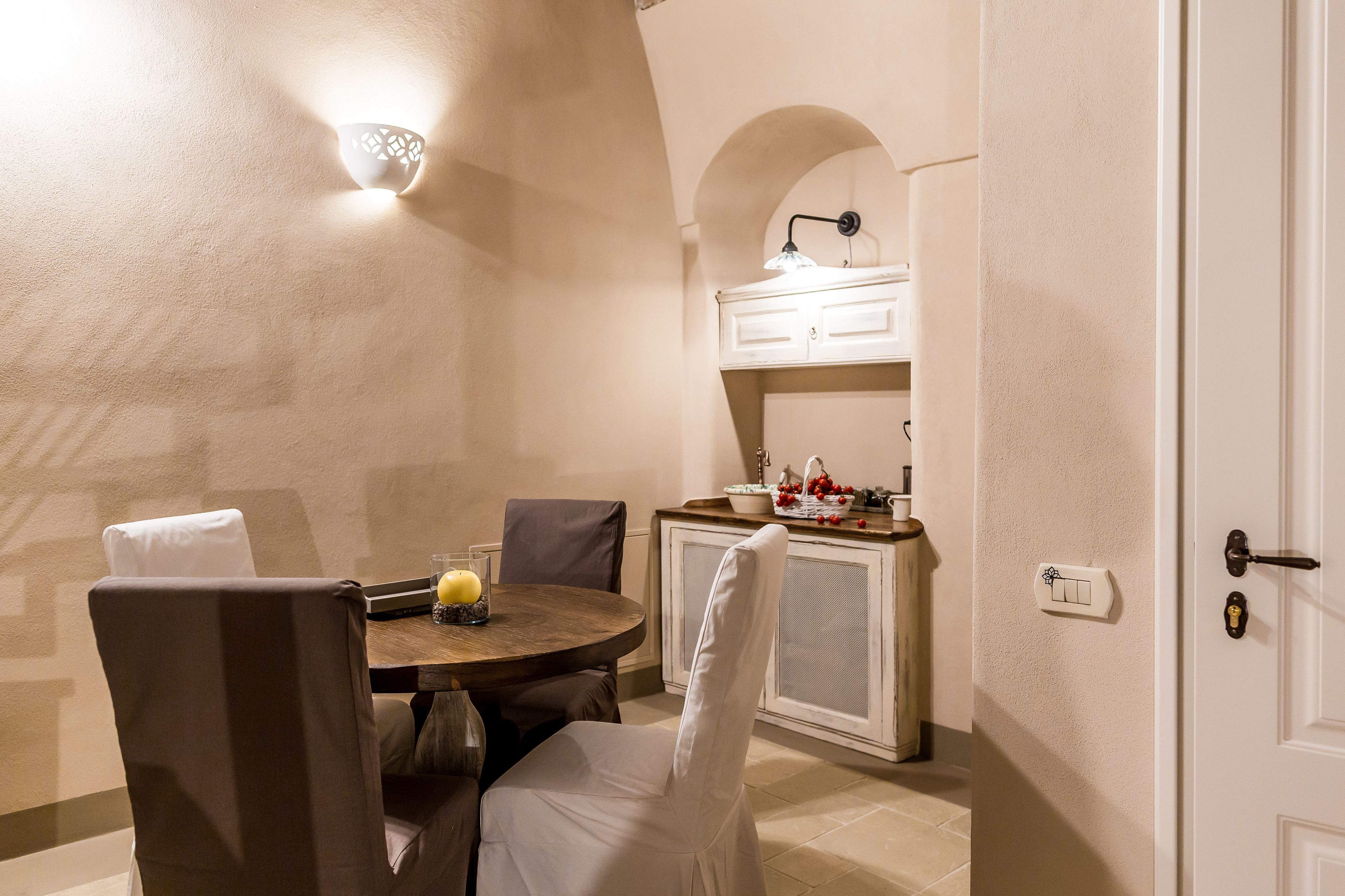 A dining area with a round table, chairs, and a wall-mounted light fixture.