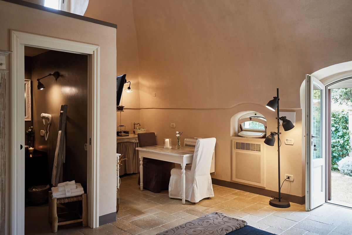 A bathroom with a sink, mirror, towel rack, and a small table with a candle.