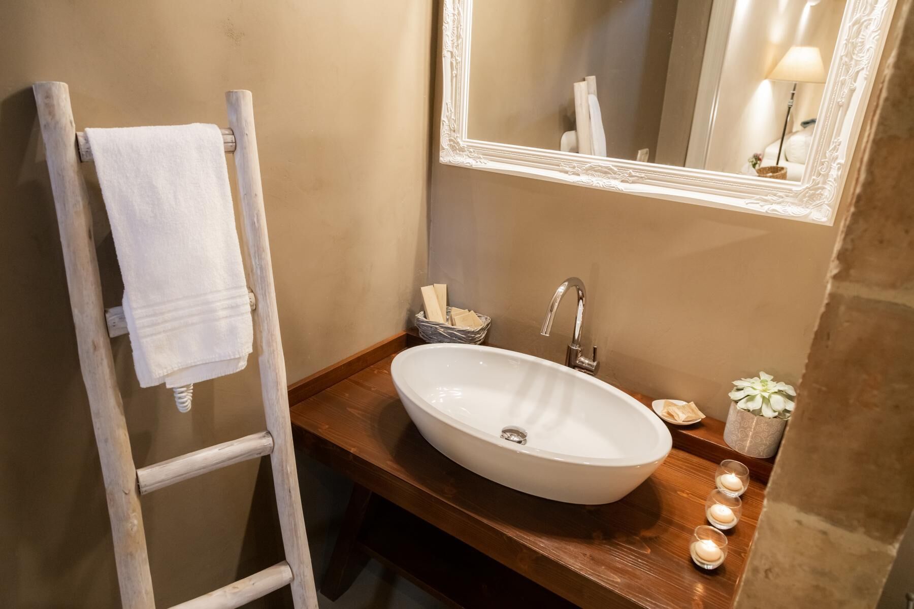 A bathroom with a wooden vanity, a white sink, a mirror, and a towel rack.
