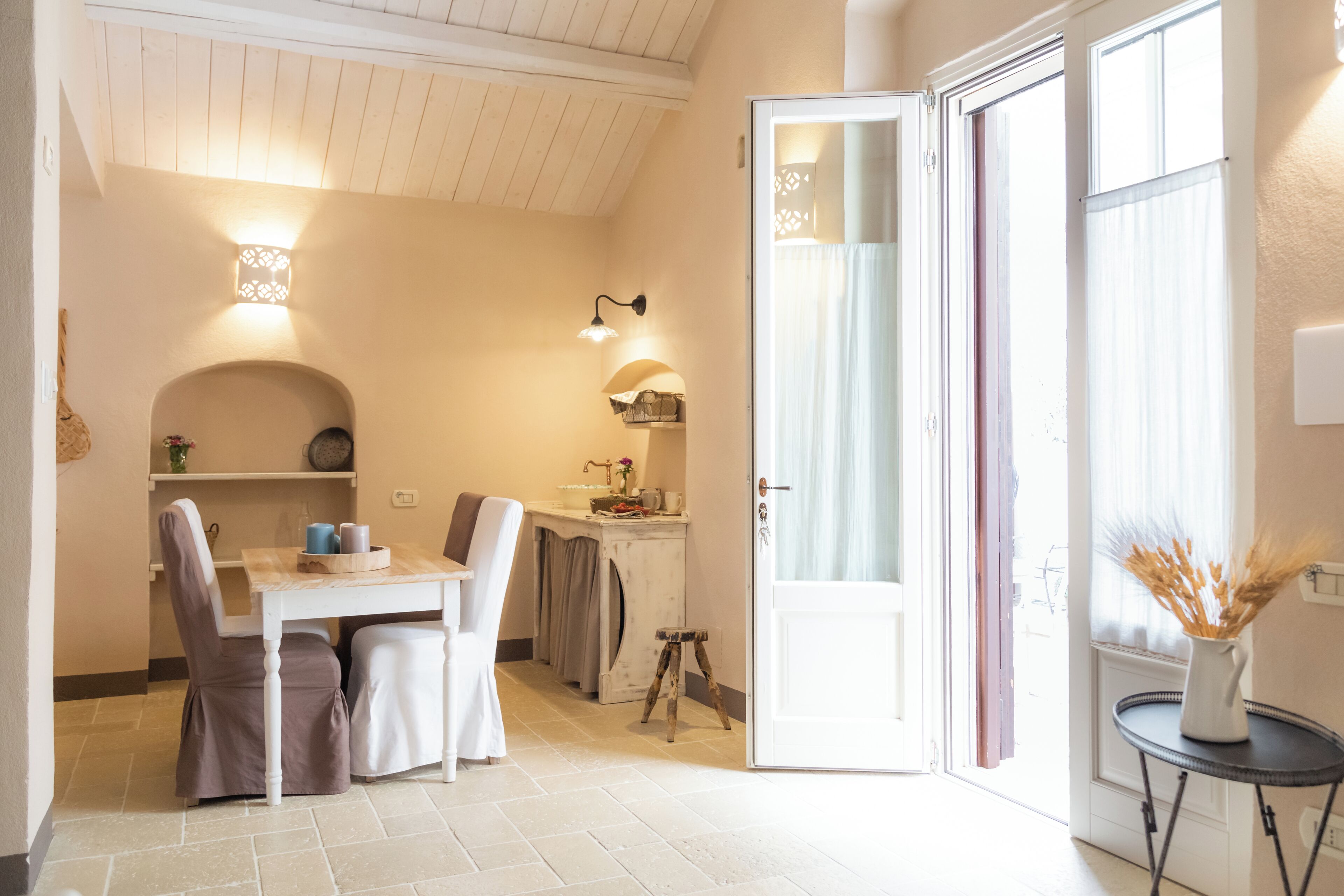 A cozy room with a dining area, a small kitchen, and a door leading to an outdoor area.