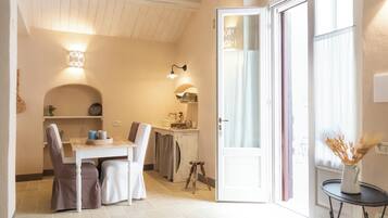 A cozy room with a dining area, a small kitchen, and a door leading to an outdoor area.