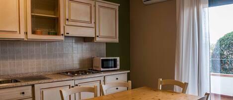 A kitchen with wooden cabinets, a microwave, and a dining table with chairs.