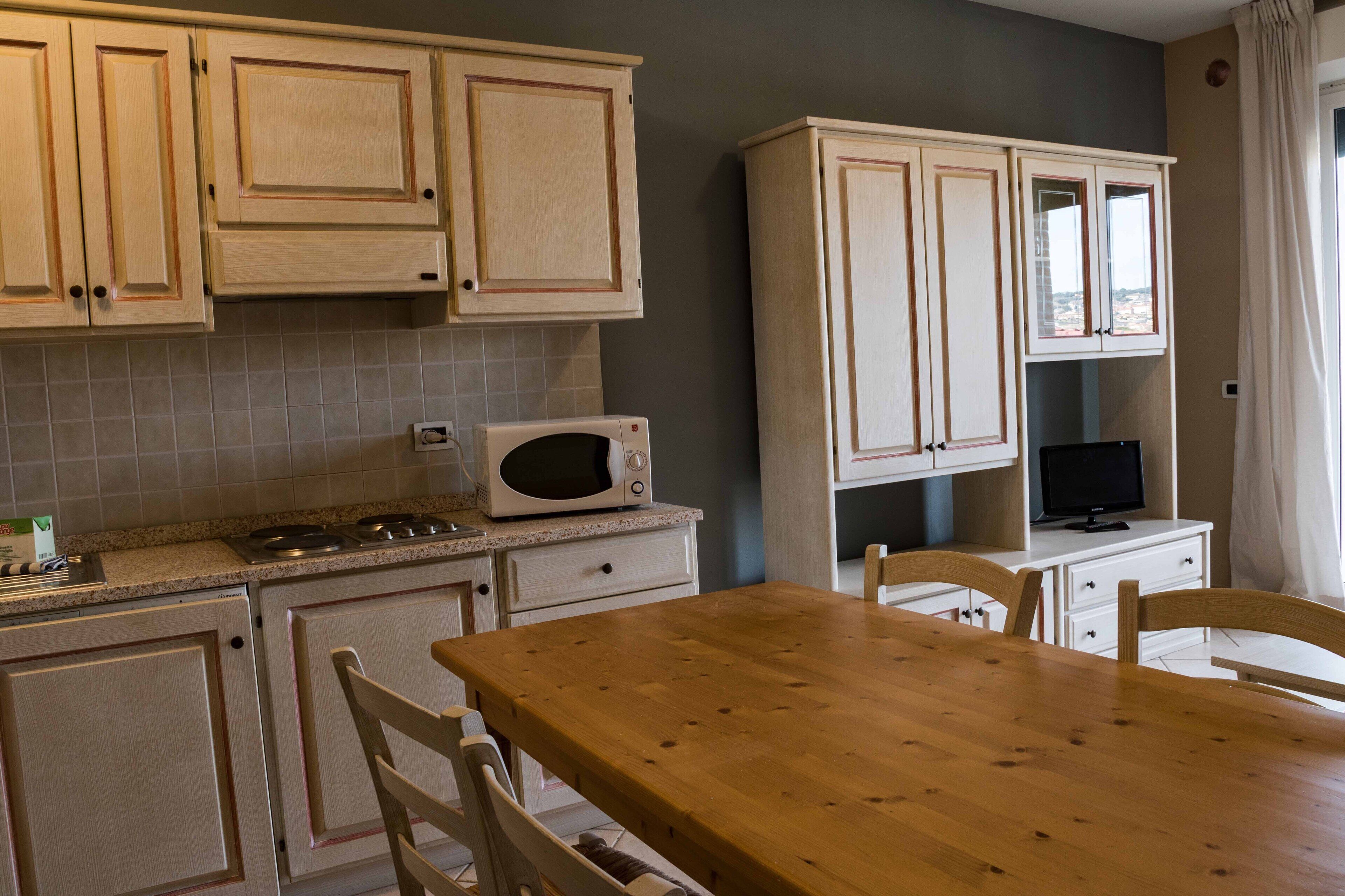 A kitchen with wooden cabinets, a microwave, a stove, and a dining table with chairs.