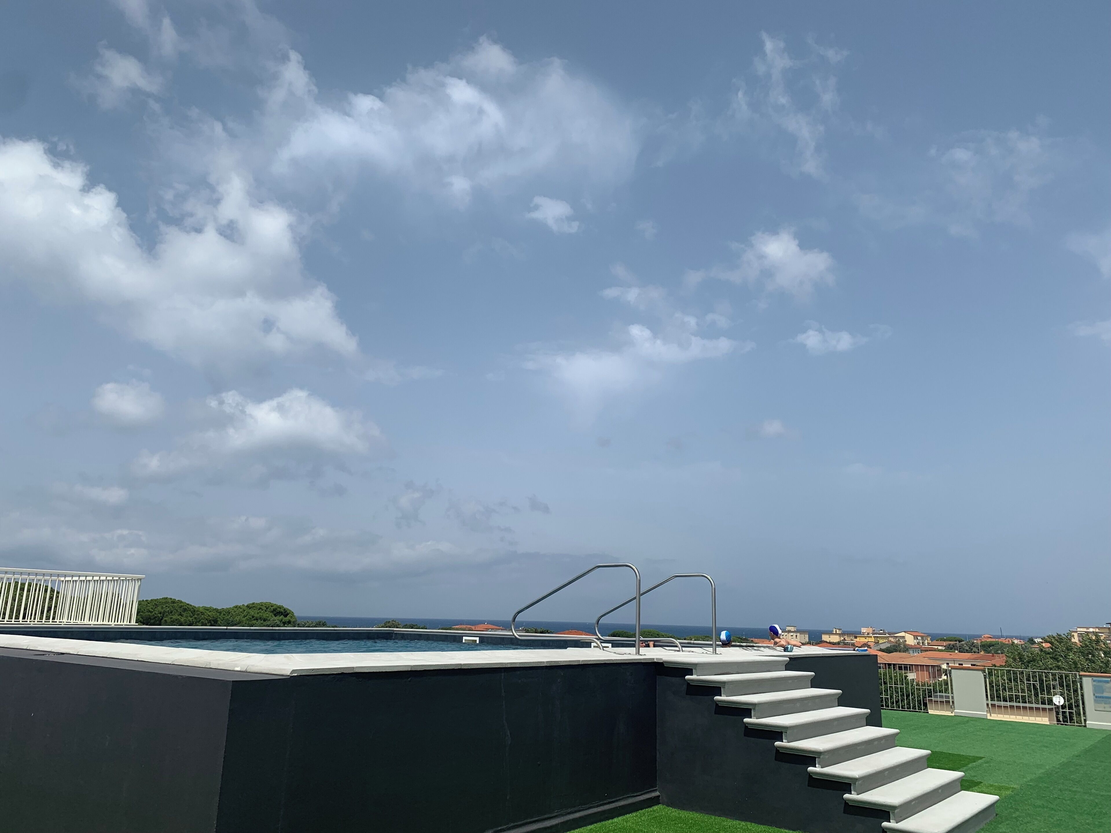 Une piscine sur le toit offrant une vue sur la mer et les bâtiments au loin.