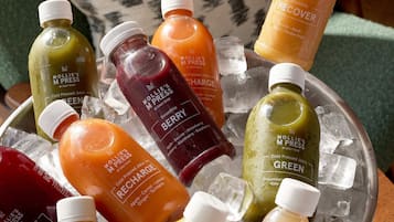 A variety of cold-pressed juices in a metal container with ice cubes.