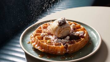 Un plato de waffles con jarabe, una bola de helado y un poco de azúcar glas.
