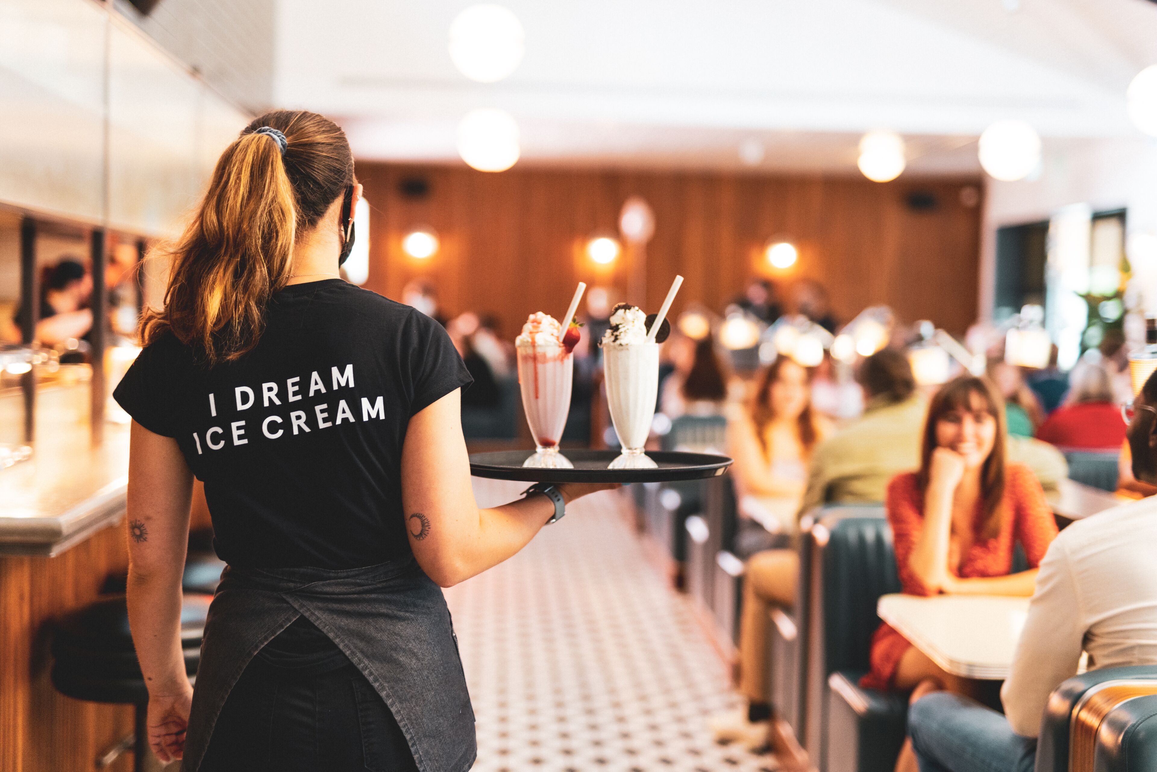 A person serving ice cream in a restaurant with a tray.