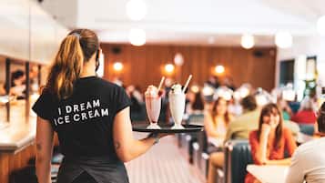 A person serving ice cream in a restaurant with a tray.
