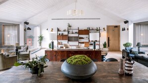 Un vaste espace de vie comprenant une table à manger en bois, un grand vase rempli de plantes et une bibliothèque au design moderne.