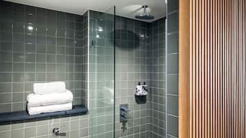 Een moderne badkamer met een douchecabine van glas, een handdoekhouder en een zeepdispenser.
