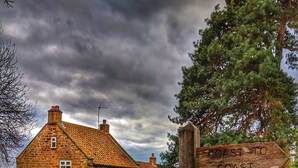 Un bâtiment rustique en pierre, agrémenté d’un panneau indiquant « De la côte à l’autre ».