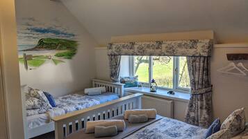 Un dormitorio con dos camas individuales, una cama grande, una ventana con cortinas, un radiador y un mural en la pared.