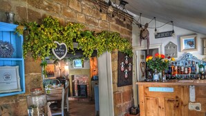 Un coin bar au style rustique, avec un comptoir en bois, un mur en briques et un luminaire suspendu.