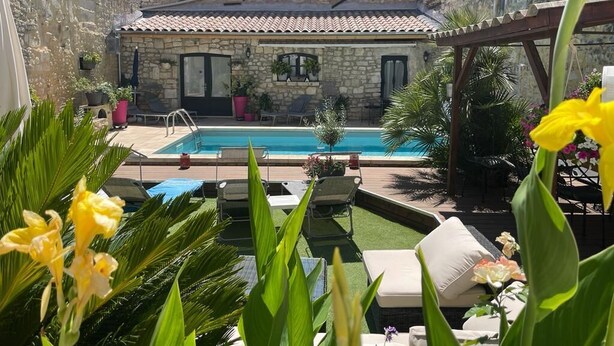 Un bâtiment en pierre doté d’une piscine, d’un espace extérieur aménagé et d’une végétation luxuriante.