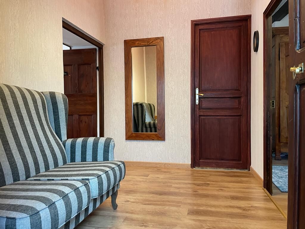 A hallway with a striped sofa, a wooden door, and a mirror on the wall.