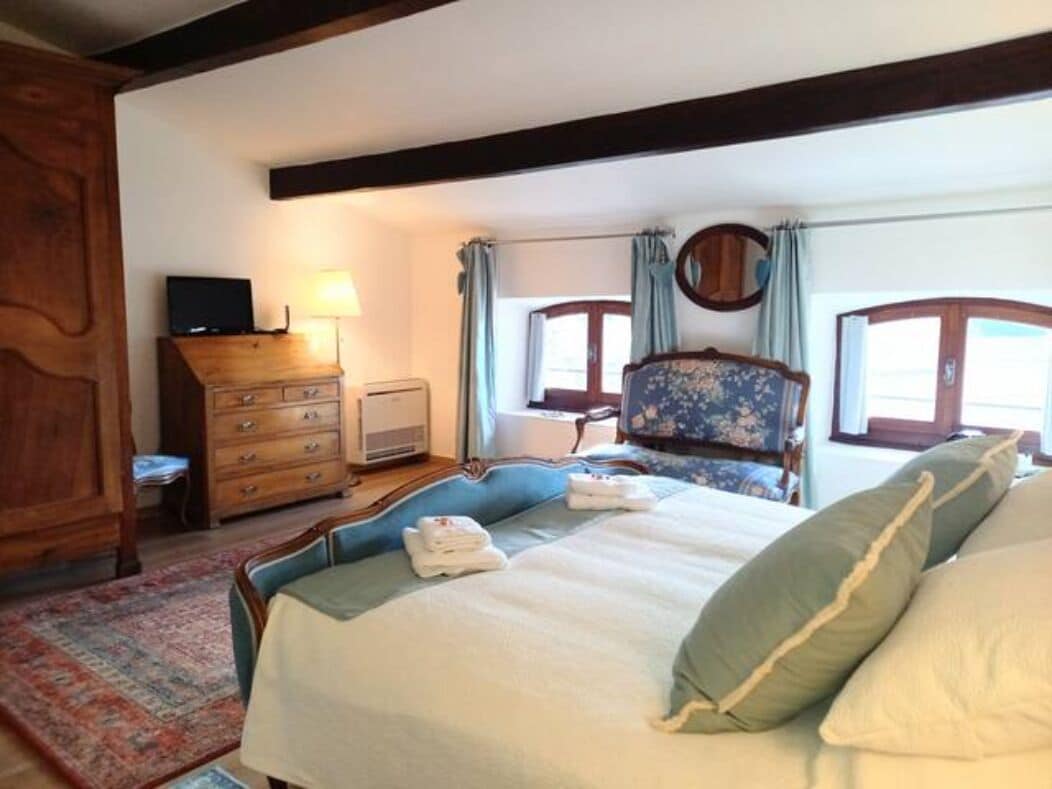 A bedroom with a bed, a dresser, a chair, and a television.