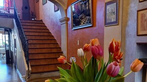Un escalier avec une rampe, un vase de tulipes et un tableau encadré accroché au mur.