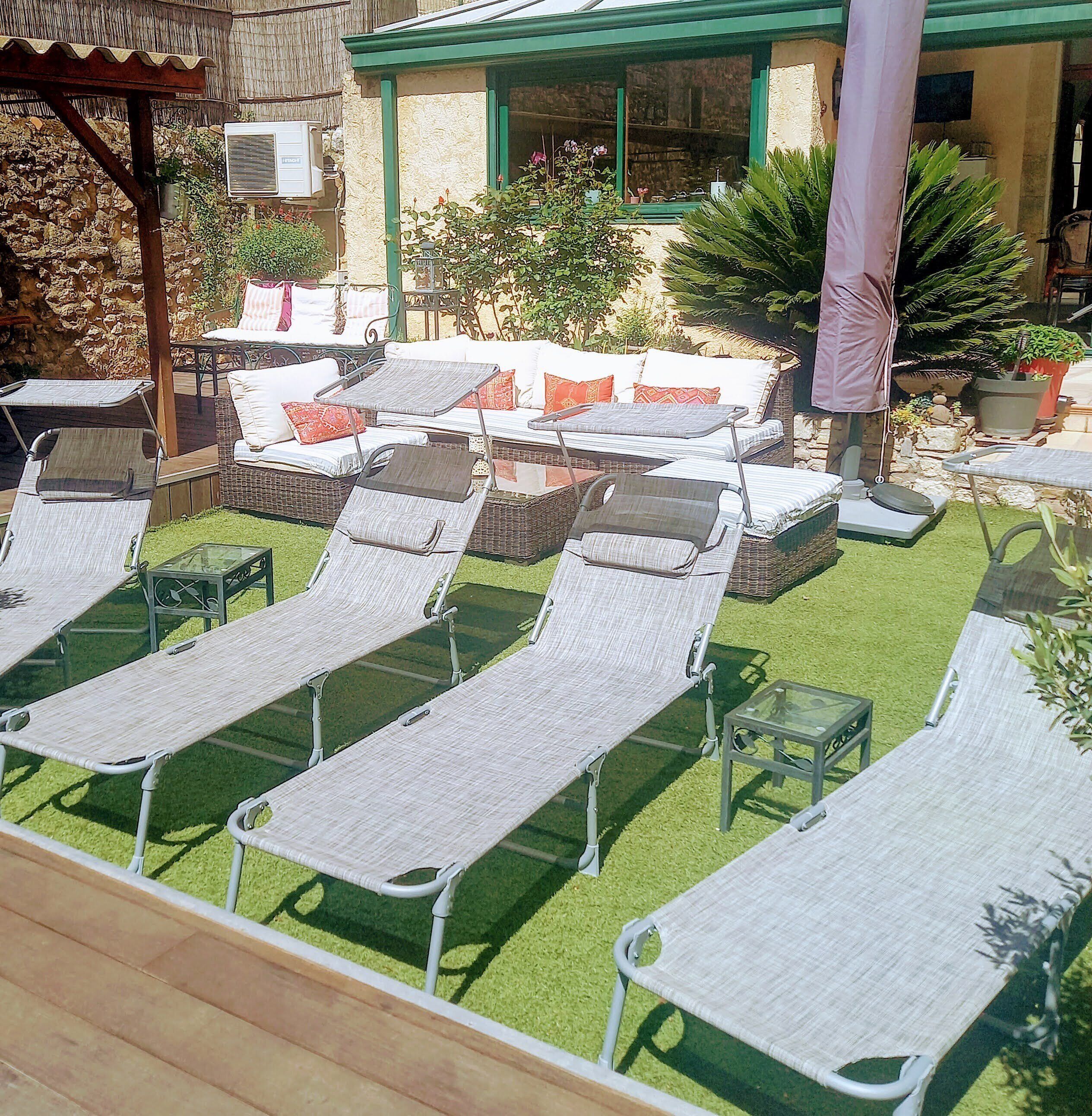 A sunlit outdoor seating area with lounge chairs and a covered patio.
