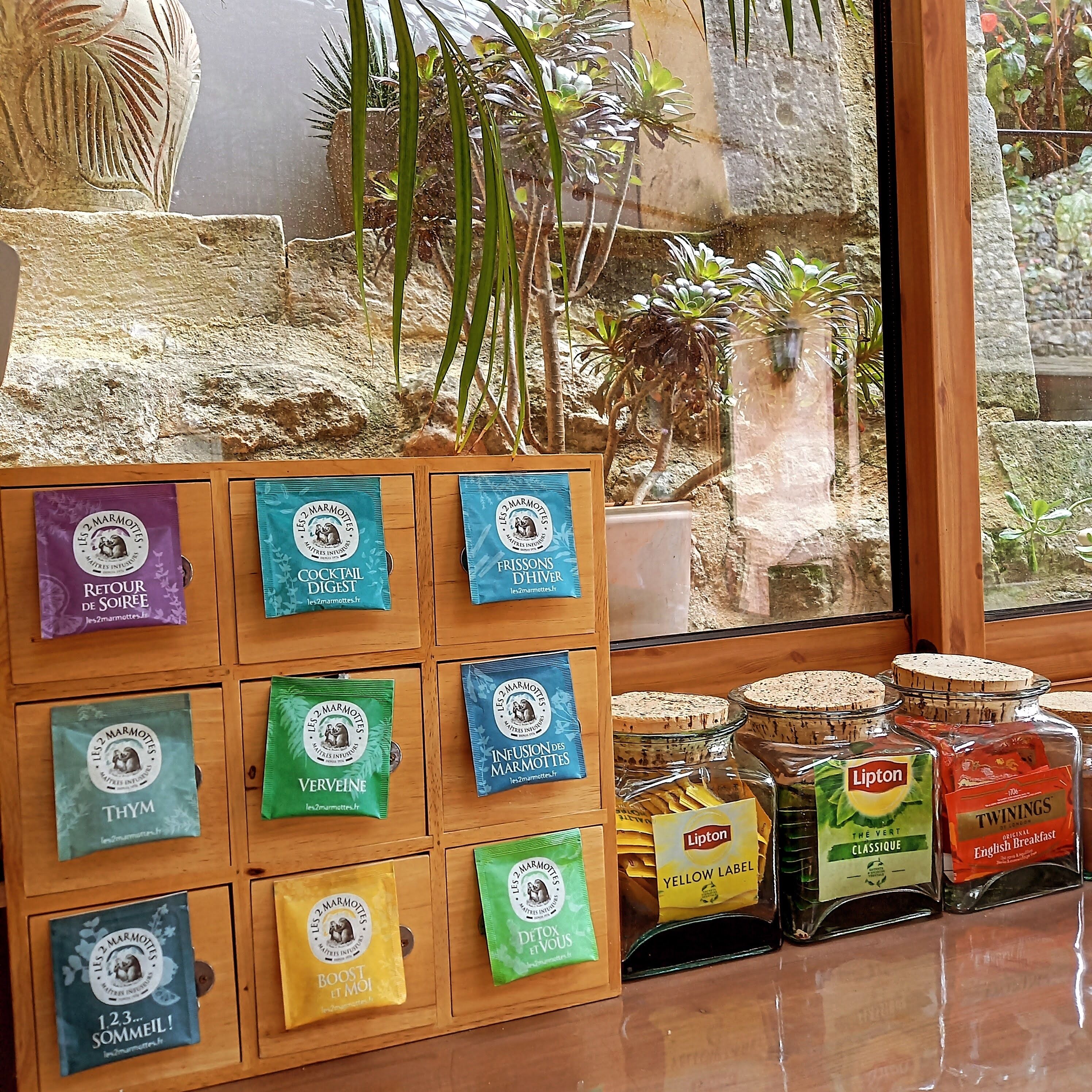 A display of various marmottes products in a store with a stone wall and plants in the background.