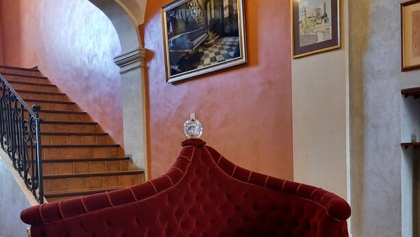 Ein rotes Samtsofa in einer Lobby mit einer Treppe und einem Bild an der Wand.