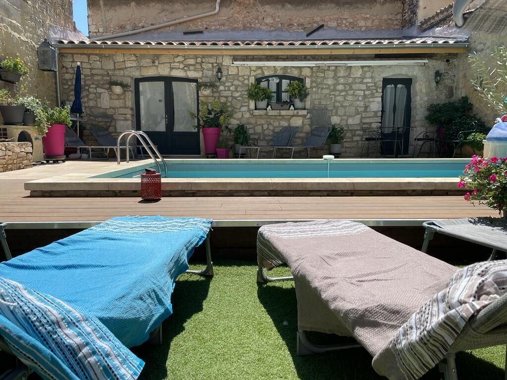 A poolside area with a stone building, lounge chairs, and a wooden deck.